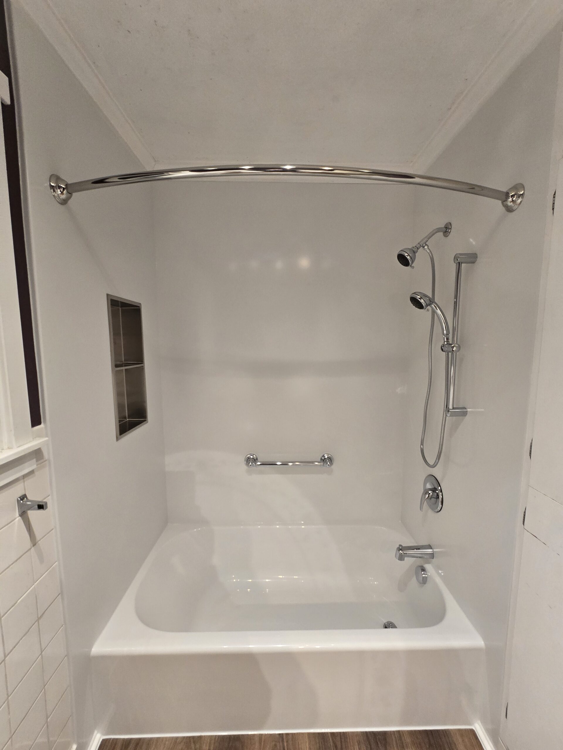 White acrylic shower with a handheld showerhead and silver curtain rod