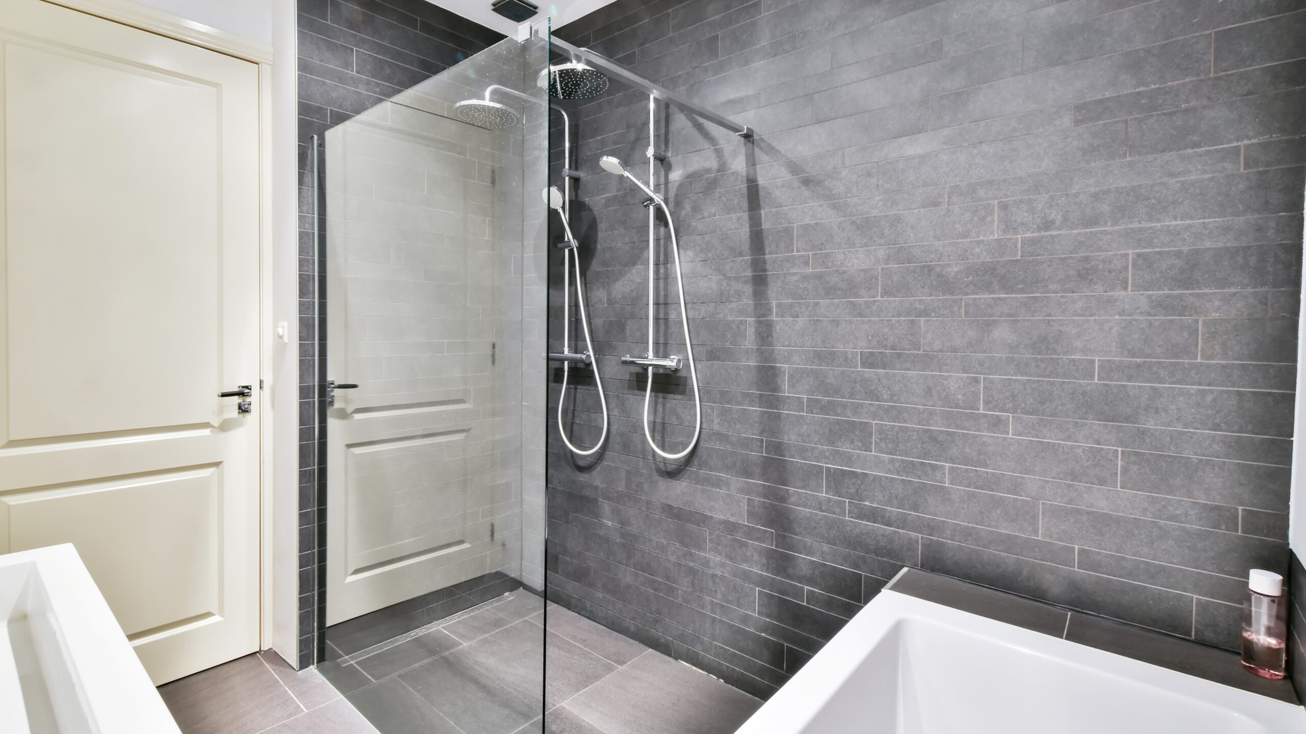Bathroom with white interior with white framed windows, white sink, and shower with glass enclosure and patterned wallpaper interior