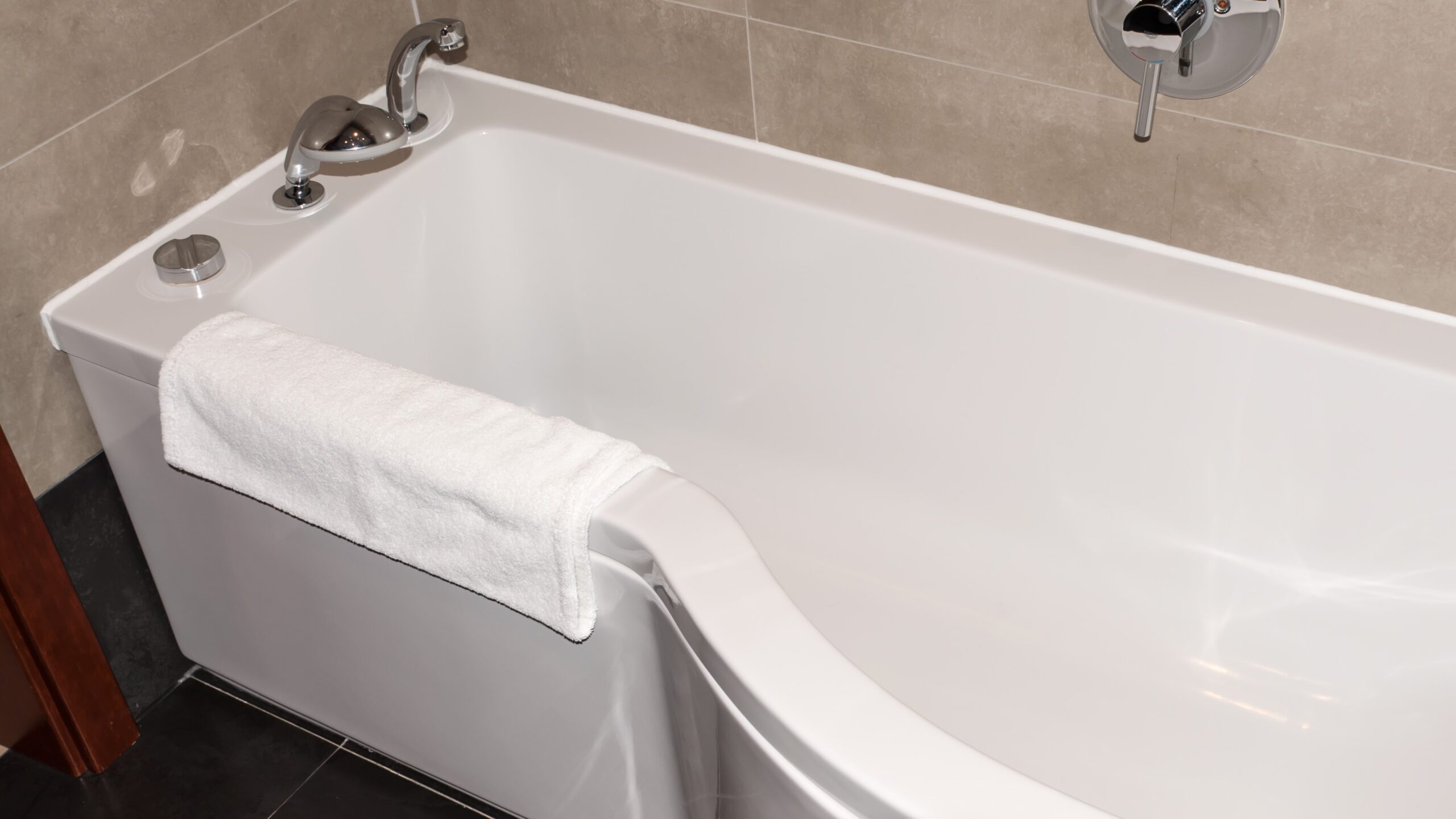 Close-up view of white bathtub with beige tile walls