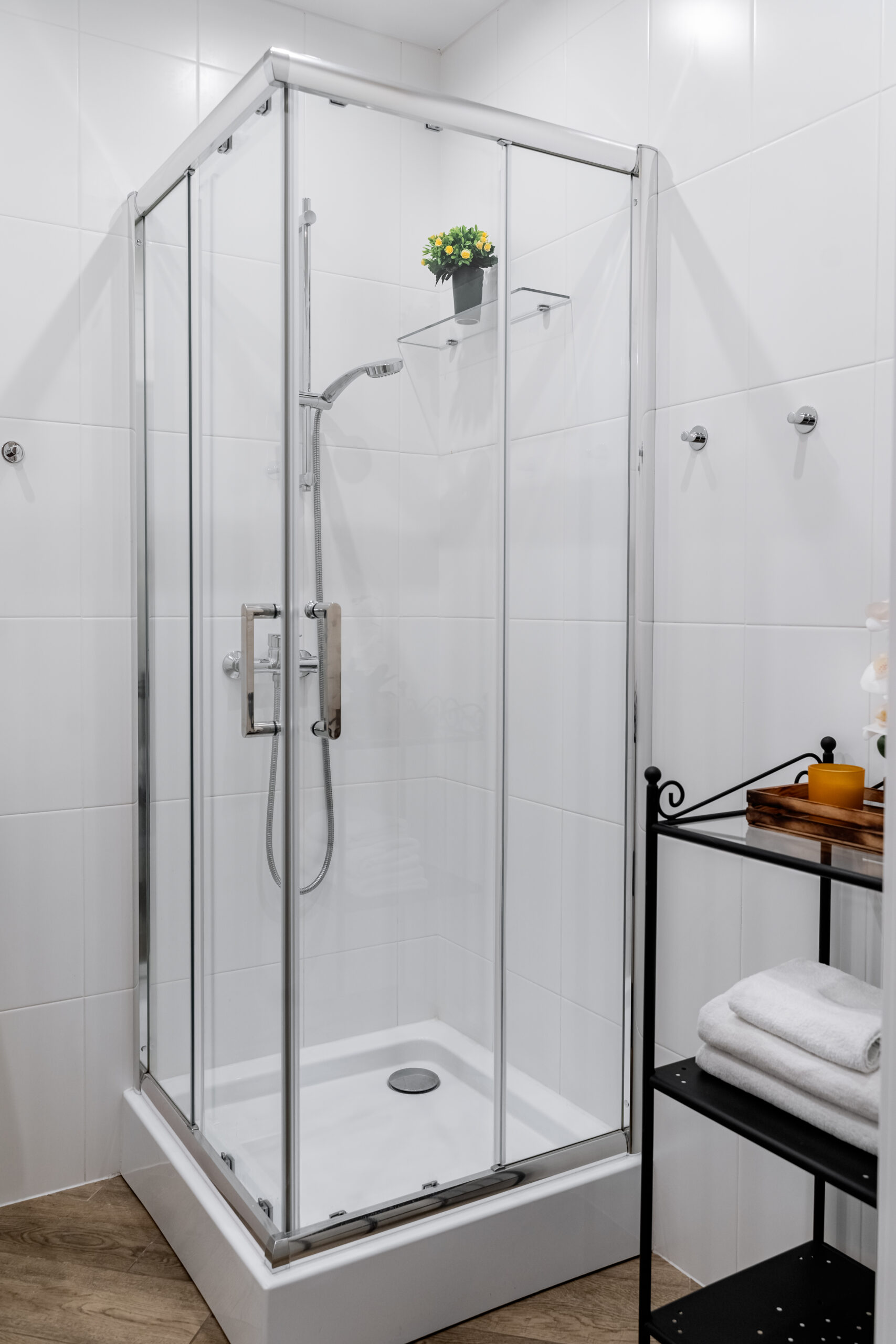 Corner shower with glass shower door and chrome hardware