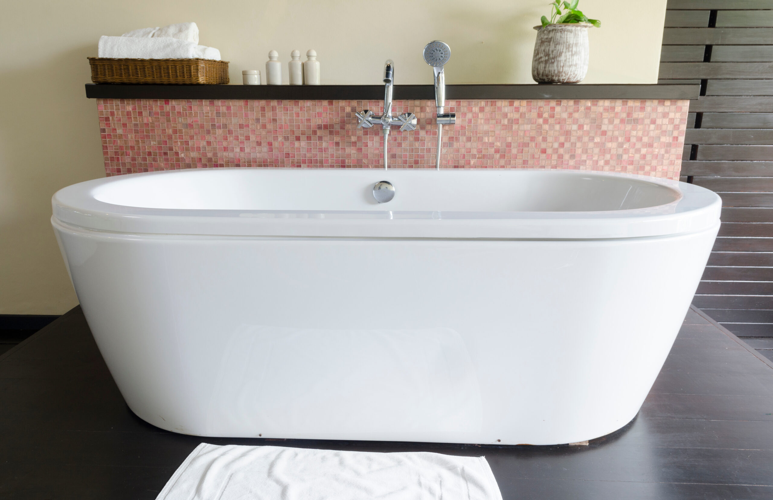 Close-up of a white freestanding tub in front of a bathroom shelf