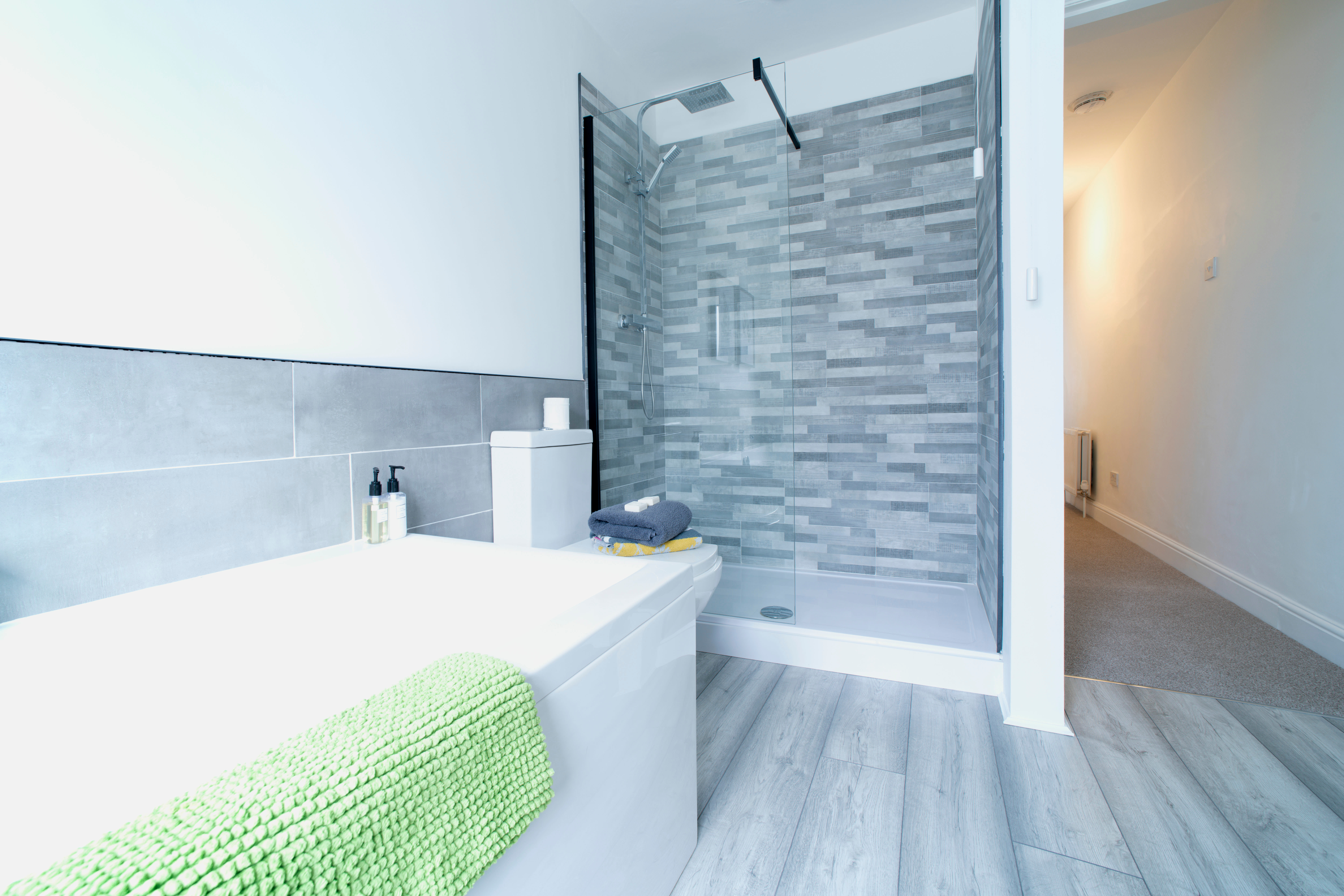 New walk-in shower with gray backsplash beside a bathtub