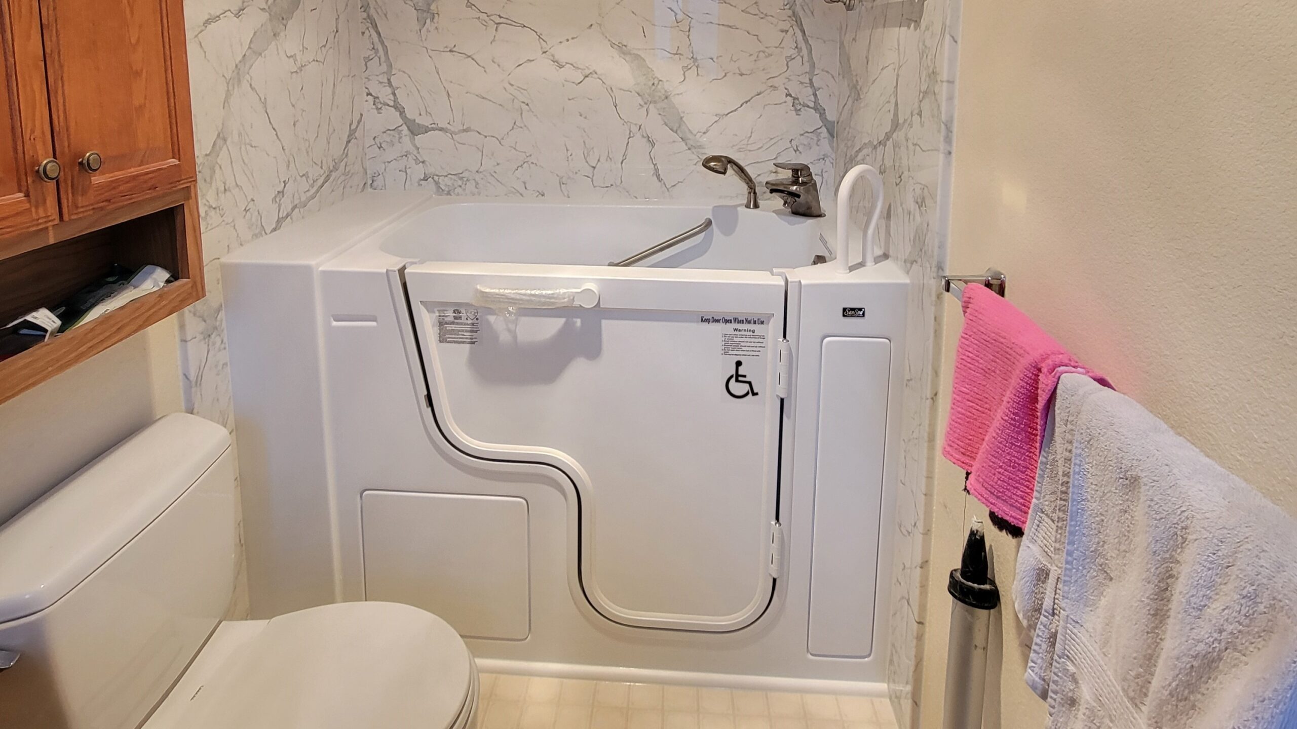 New white walk-in tub installation with beautiful marble-esque acrylic surround